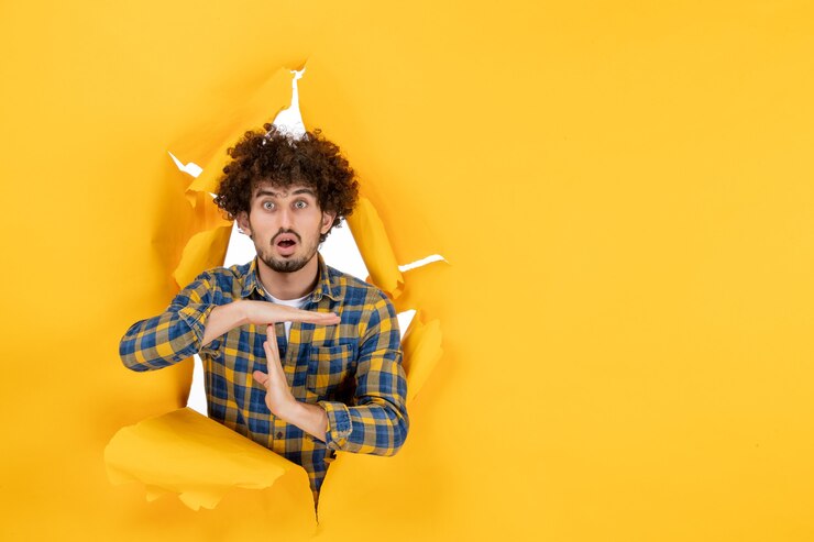 मुफ़्त फोटो front view young male showing t letter on yellow ripped background