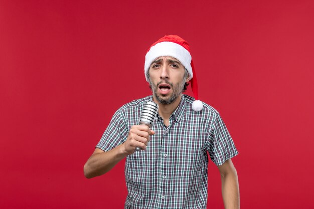 Front view young male singing with mic on red background