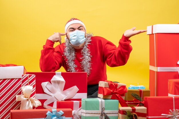 Free photo front view young male sitting around presents in mask on yellow