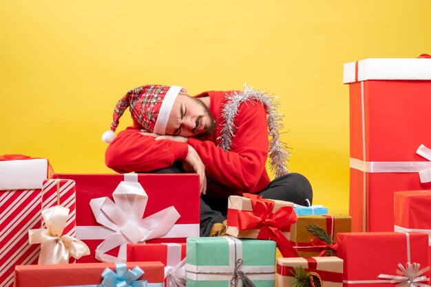 Front view young male sitting around presents sleeping on yellow background