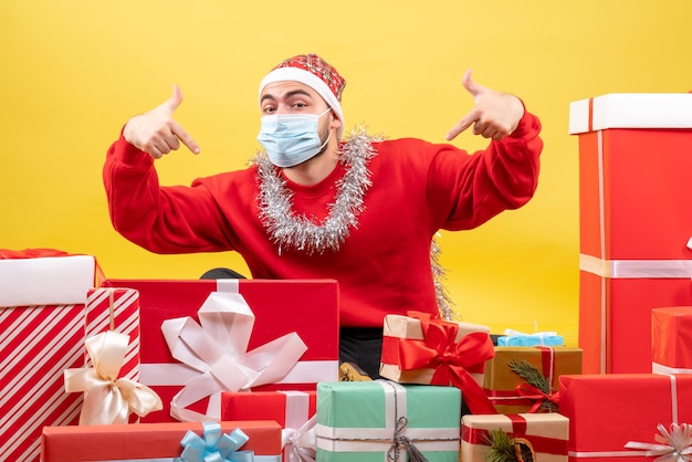 Free photo front view young male sitting around presents on yellow background