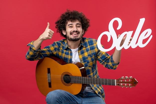 빨간 벽 음악 판매 재생 콘서트 박수 음악가 색상에 기타와 함께 앉아 전면보기 젊은 남성