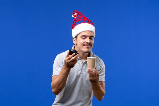 Front view young male smelling coffee on blue wall new year male holiday emotions