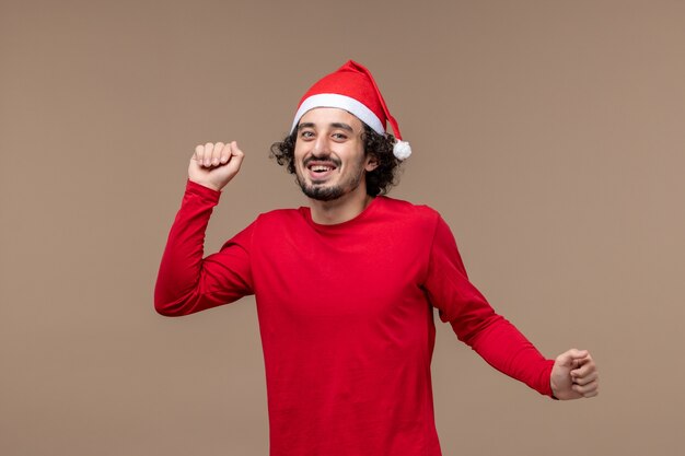 Вид спереди молодой мужчина улыбается на коричневом фоне эмоции рождественских праздников