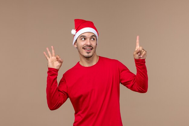 正面図茶色の背景の休日のクリスマスの感情に笑みを浮かべて若い男性