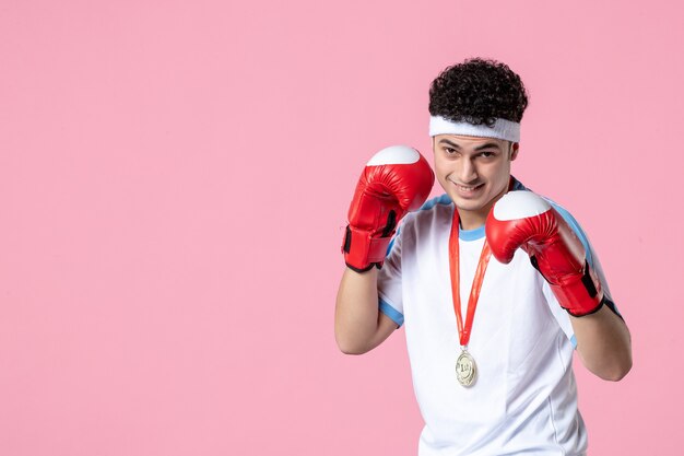 Front view young male in sport clothes and boxing gloves on pink wall