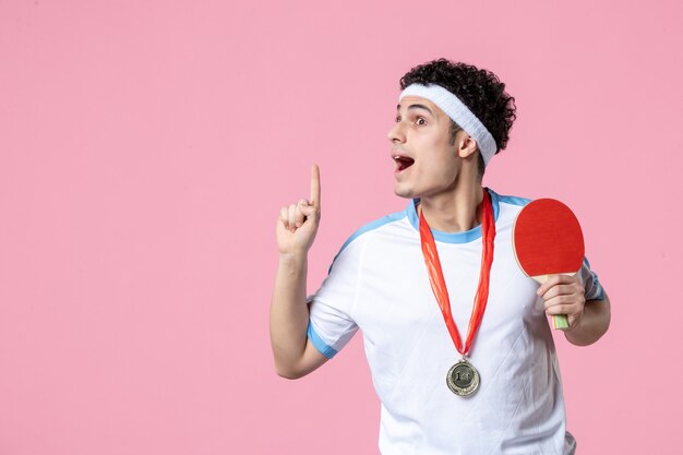 ピンクの壁にメダルとスポーツ服を着た若い男性の正面図