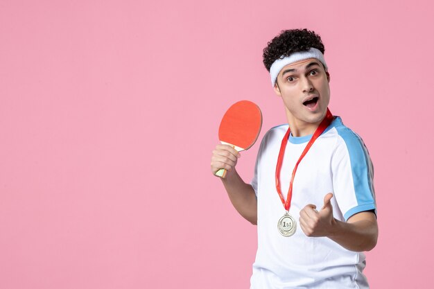 Front view young male in sport clothes with racket and medal on pink wall