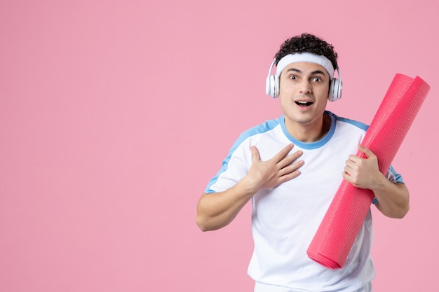 Front view young male in sport clothes with yoga mat on pink wall
