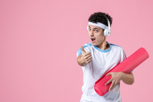 Front view young male in sport clothes with yoga mat on pink wall