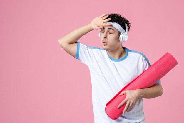 Front view young male in sport clothes with yoga mat on pink wall