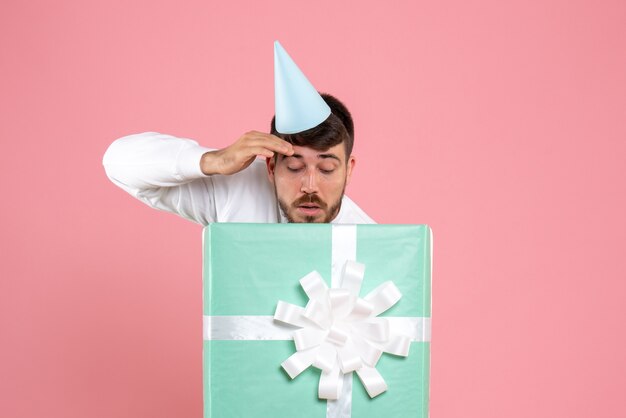 Front view young male standing inside present box on light pink photo color human emotion xmas pajama party