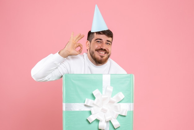 Front view young male standing inside present box on the pink photo color emotion xmas pajama party