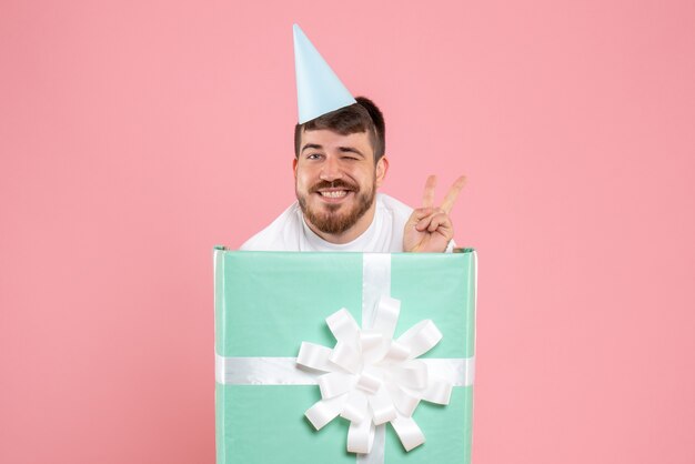 ピンクのクリスマスの写真の色の感情のパジャマパーティーのプレゼントボックスの中に立っている正面図若い男性