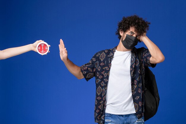 Free photo front view young male student wearing black mask with backpack on light-blue background.