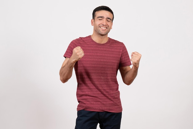 Front view young male in t-shirt posing and rejoicing on white background