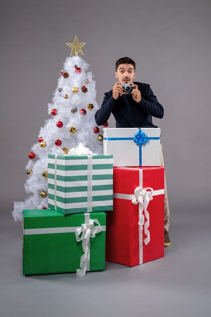 灰色のプレゼントと写真を撮る正面図若い男性