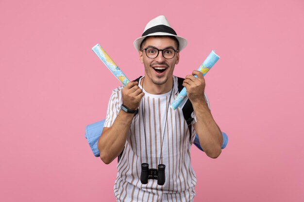 Free photo front view young male tourist holding maps on pink background