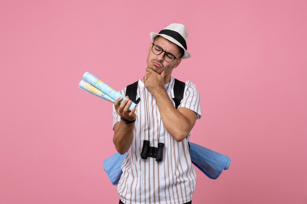 Front view young male tourist holding maps on pink background