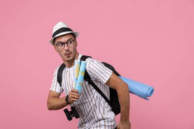 Free photo front view young male tourist holding maps on pink desk