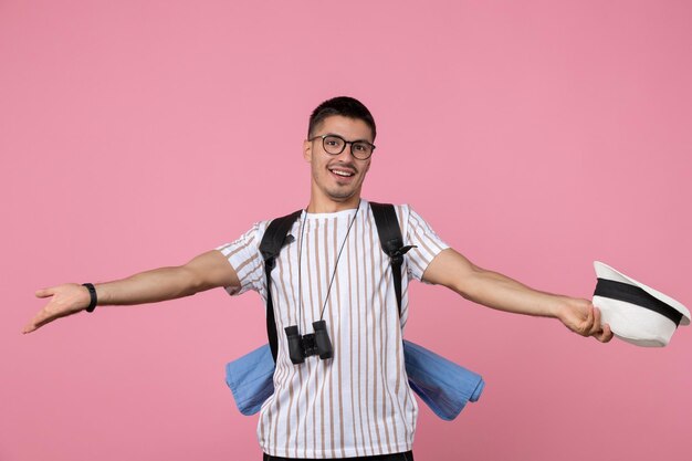 Front view young male tourist taking off his hat on a pink background