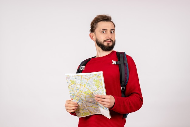 Front view young male tourist with backpack exploring map on white wall plane city vacation emotion human color route