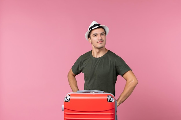 ピンクのスペースに帽子をかぶって休暇中の若い男性の正面図