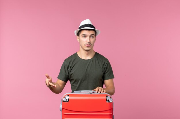 Вид спереди молодой самец в отпуске с большой сумкой на розовом пространстве