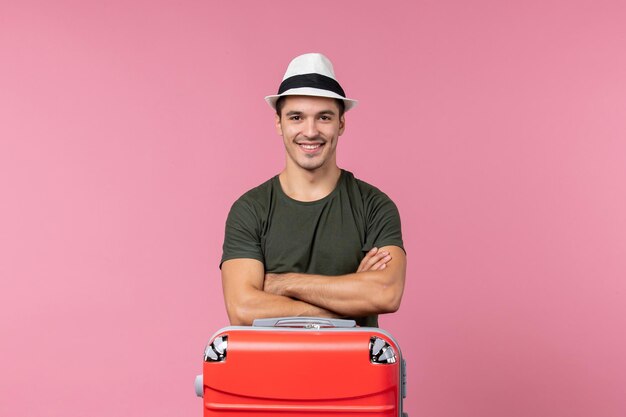 Вид спереди молодой мужчина в отпуске в шляпе, улыбаясь в розовом пространстве