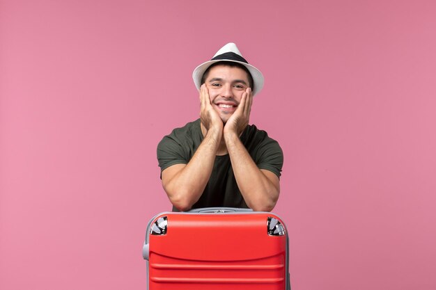 Front view young male in vacation with his red bag and smiling on a pink space