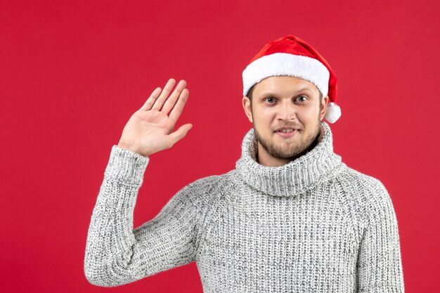 Front view young male in warm jersey greeting on red wall