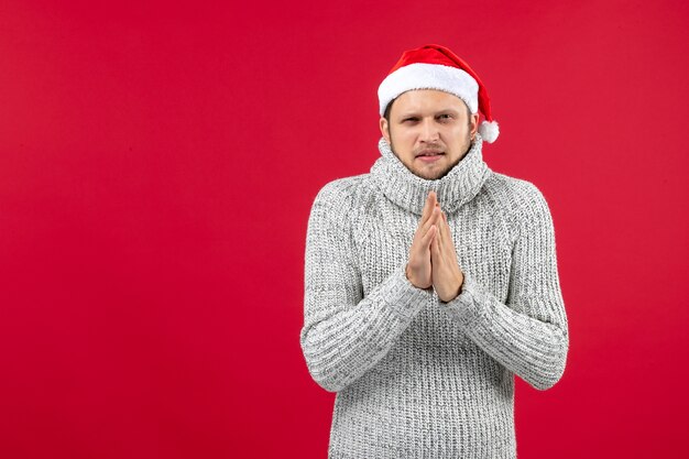 Front view young male in warm jersey shivering from cold on a red background