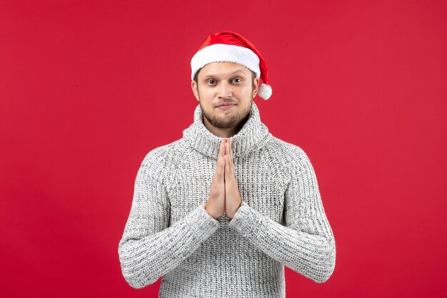 Front view young male in warm jersey with holiday cap on a red background