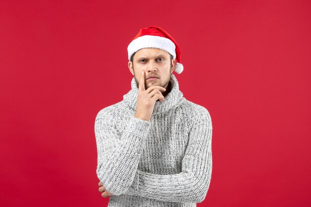 Front view young male in warm jersey with holiday cap thinking on red background