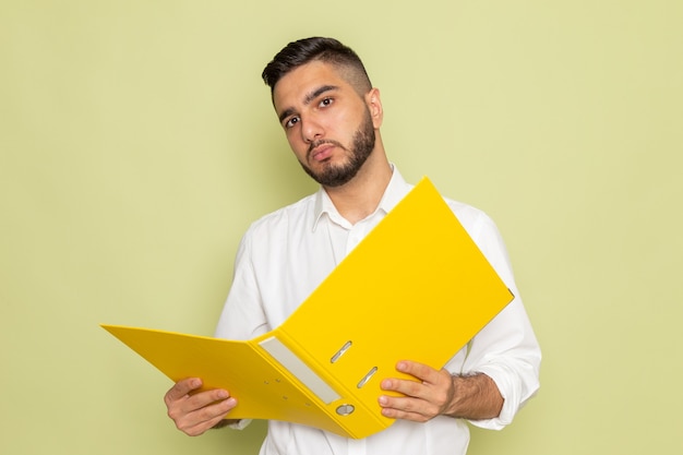 A front view young male in white shirt holding yellow files