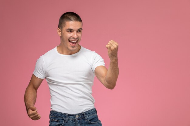 Вид спереди молодой мужчина в белой рубашке, эмоционально смеющийся на светло-розовом фоне