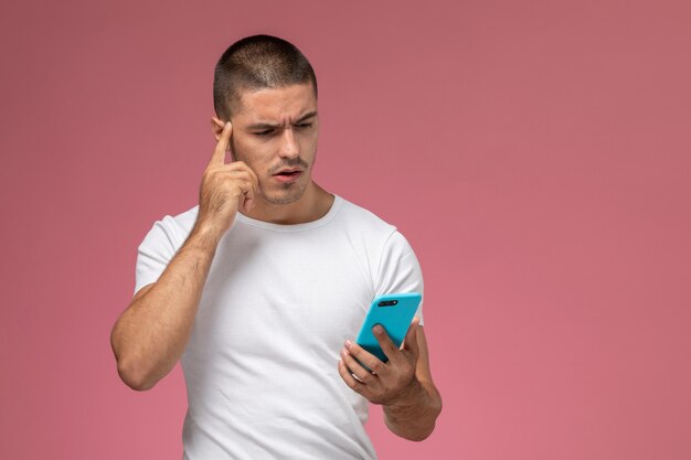 Front view young male in white shirt using his phone on pink background 