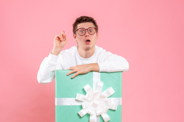 Front view young male in white shirt with present on pink background