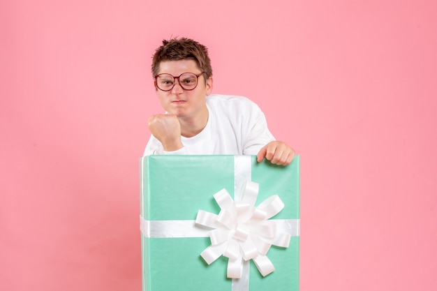 Front view young male in white shirt with present on pink background