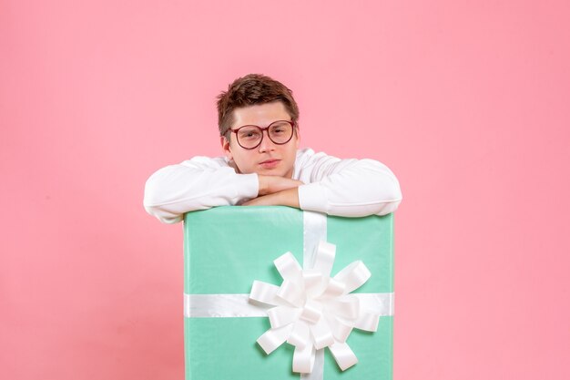 Front view young male in white shirt with present on the pink background