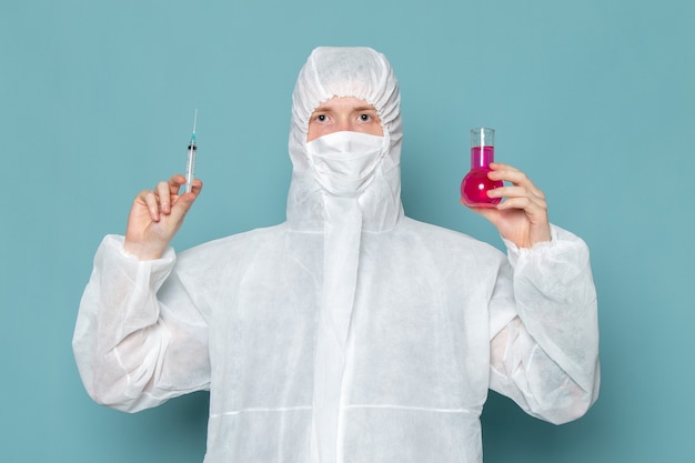 A front view young male in white special suit and holding solutions and injections on the blue wall man suit danger special equipment color