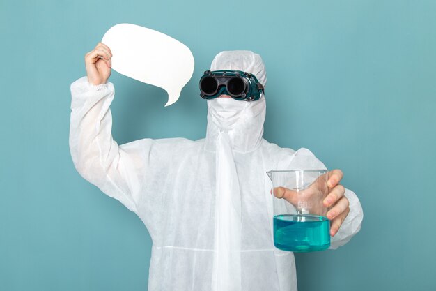 A front view young male in white special suit and holding white sign and solution on the blue wall man suit danger special equipment color