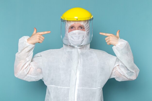 A front view young male in white special suit wearing special head mask on the blue wall man suit danger special equipment color