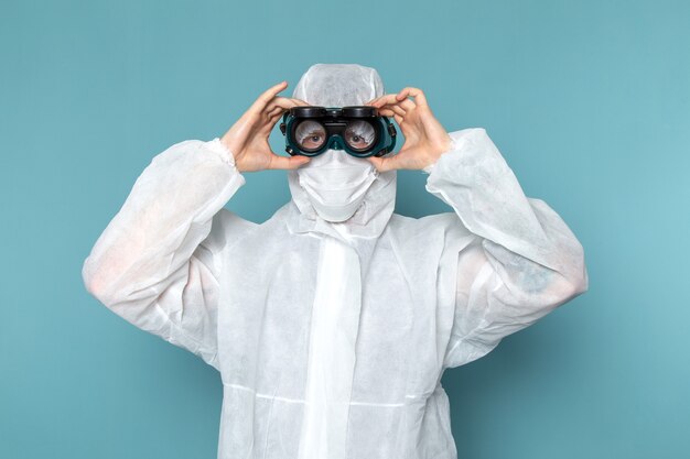 A front view young male in white special suit wearing special sunglasses on the blue wall man suit danger special equipment color