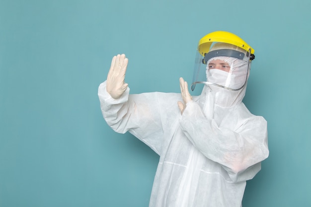 A front view young male in white special suit and yellow special helmet on the blue wall man suit danger special equipment color