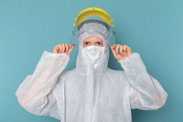 A front view young male in white special suit and yellow special helmet on the blue wall man suit danger special equipment color