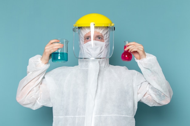 Free photo a front view young male in white special suit and yellow special helmet holding solutions on the blue wall man suit danger special equipment color