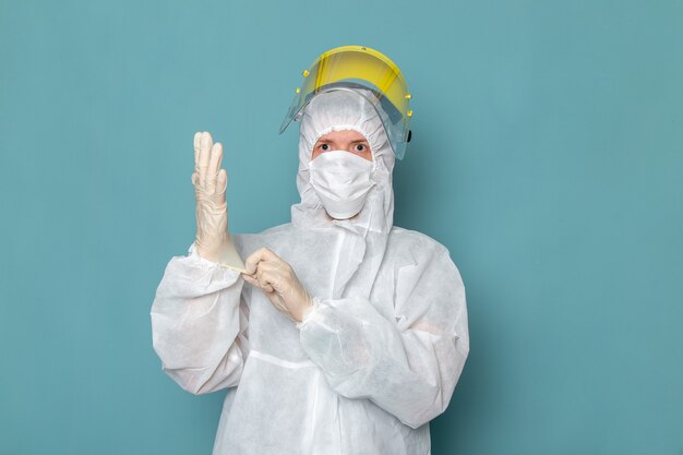 A front view young male in white special suit and yellow special helmet wearing white gloves on the blue wall man suit danger special equipment color