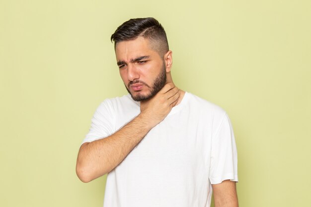 A front view young male in white t-shirt having throat issues