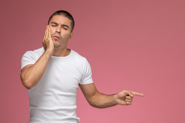 Front view young male in white t-shirt having a toothache on pink background  